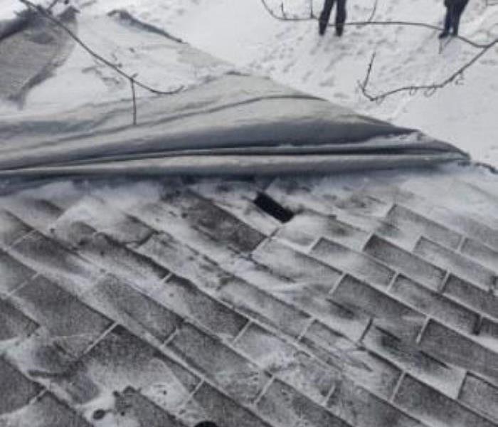 Pictured is a roof that was punctured from a tree that had fallen as a result of a storm.