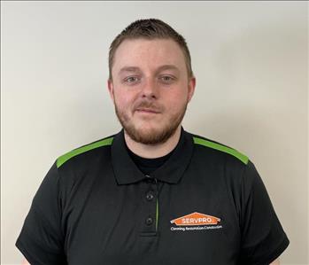Man with dark hair and beard smiling for employee photo with a black and green Servpro polo on. 